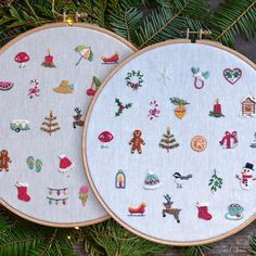 two embroidery hoops with christmas designs on them hanging from a pine tree, next to each other