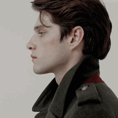 a young man in a pea coat looking off into the distance with his eyes closed