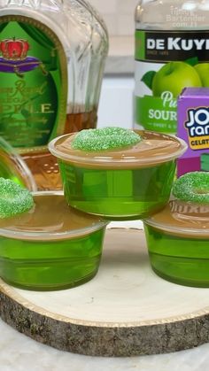 green jello cups sitting on top of a wooden tray