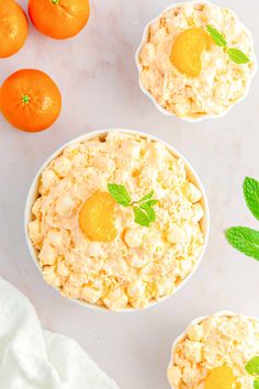 three small white bowls filled with food next to oranges and mint leafy garnish