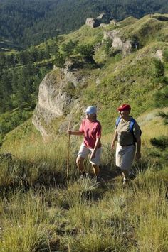 two hikers trekking up a steep hill in the mountains