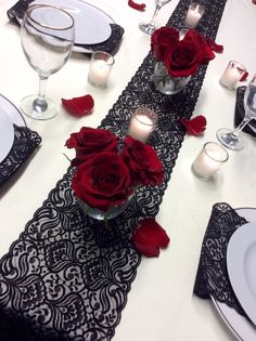 the table is set with red roses and candles