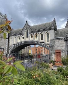 an arched stone bridge over a lush green park filled with lots of plants and flowers