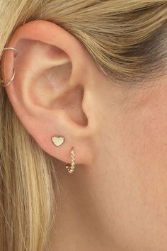 a close up of a woman's ear with two small gold hearts on it