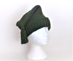 a white mannequin head wearing a green knitted hat with tassels