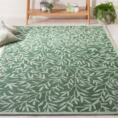 a green rug with white leaves on it in front of a wooden shelf and plant