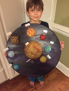 a young boy holding up a plate with planets on it