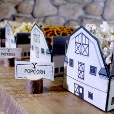 some paper houses are sitting on a table with popcorn in front of them and other items