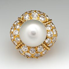 This magnificent cocktail ring is centered with one (1), post set, cultured South Sea pearl. The pearl tops a domed setting is bead set sixty-four (64), bead set, round brilliant cut diamonds. The ring has a split shank design and is accented with seven (7), bead set, round brilliant cut diamonds on each side. The ring measures 21.7mm at the top, rises 18.6mm above the finger, tapering to 2.4mm wide and 1.1mm thick at the base of the shank. The ring is currently size 7. Elegant White Domed Rings, Elegant White Domed Jewelry, Classic Cabochon Pearl Ring For Formal Occasions, Classic Formal Pearl Ring With Cabochon, Luxury Cabochon Pearl Ring For Wedding, White Pearl Ring With 17 Jewels For Formal Occasions, Luxury Cabochon Pearl Wedding Ring, Elegant Round Cabochon Pearl Ring, Luxury Pearl Cabochon Ring For Formal Occasions