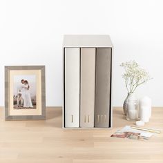 a couple is posing in front of a bookcase on the table next to a vase with baby's breath flowers