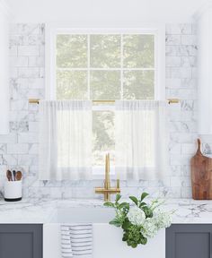 a kitchen with marble counter tops and white cabinets, along with a window over the sink