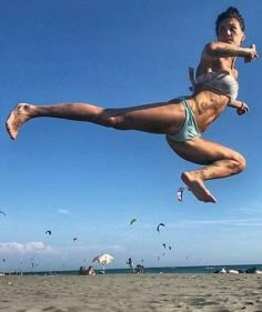 a woman is jumping in the air at the beach