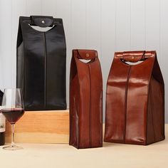 two wine bags sitting next to each other on top of a table with a glass of wine in front of them