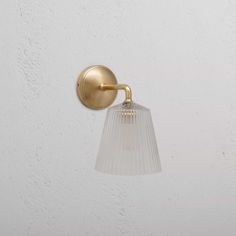 a light that is on the side of a wall with a glass shade hanging from it