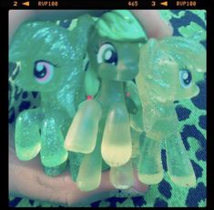 there are three little pony toys in the palm of someone's hand, one green and one yellow