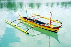 a yellow and red boat with two oars floating on water