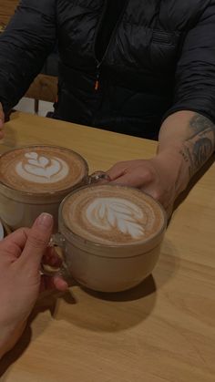 two people sitting at a table with cups of coffee