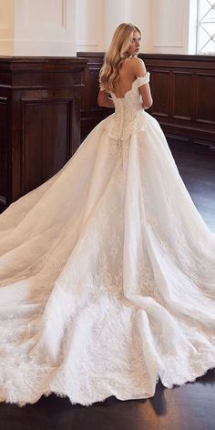 a woman in a white wedding dress standing on a wooden floor with her back to the camera