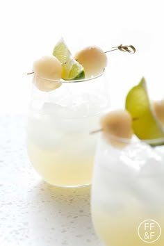 a glass filled with lemonade and limes on top of a white tablecloth