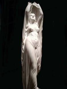 the statue is white and has a woman's head in her hands, with one arm raised