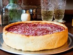 a deep dish pizza sitting on top of a metal plate next to two wine glasses