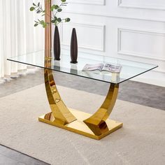 a glass table with gold metal legs and a vase on the floor next to it