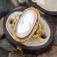 This shell cameo ring is crafted in 10k yellow gold and features a bezel set cameo decorated with seed pearl accents and engraved shoulders. The ring is currently a size 3 and we offer free resizing. The seed pearls are strung on a sturdy copper wire. Antique Oval Pearl Ring Collectible, Fine Jewelry Cameo Wedding Ring, Fine Jewelry Cameo Rings For Weddings, Victorian Cameo Rings For Wedding, Antique Oval Pearl Ring Stamped 14k, Victorian Oval Cabochon Pearl Ring, Antique Cocktail Ring, Seed Pearl Ring, Vintage Cameo