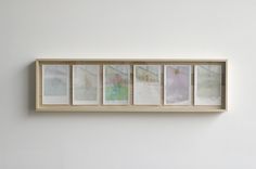 four framed photographs hang on the wall above a bench in front of a white wall