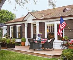 a patio with chairs, table and an american flag on the back wall in front of it