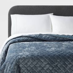 a bed with white pillows and blue quilted bedspread