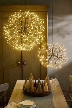 a wooden table topped with plates and bowls under a lighted clock hanging from the ceiling