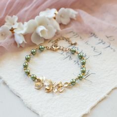 Sage Green Pearls Gold Orchid Flowers Adjustable Bracelet. This beautiful bracelet is made with high quality sage green crystal pearls and delicate matte gold plated over brass orchids. A 2" extender chain is added to the bracelet so that the length can be adjusted freely between approx. 7" and 9" (17cm-23cm). Matching necklace and matching earrings are also available from the links below.  Measurement: Bracelet length: Adjustable between approx. 7 inches and 9 inches (17cm -23cm).  Pearls: 6mm Closure: lobster claw clasp  ♥ Matching earrings: www.etsy.com/lechaim/listing/225663268 www.etsy.com/lechaim/listing/249732811 ♥ Matching necklace: www.etsy.com/lechaim/listing/470253819 ♥ More bracelets available here: www.etsy.com/shop/LeChaim?section_id=11678524 ♥Thank you for stopping by. Pleas Dainty Adjustable Green Pearl Bracelet, Elegant Green Pearl Bracelet, Green Crystal Bracelet For Wedding, Elegant Green Bracelets For Wedding, Elegant Green Wedding Bracelets, Elegant Green Beaded Pearl Bracelet, Green Pearl Jewelry For Wedding, Elegant Green Pearl Bracelet As Gift, Elegant Green Pearl Bracelet Gift