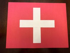 a red and white paper with a cross cut out on it sitting on a table