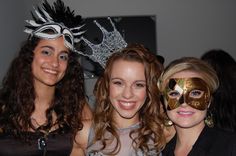 three women with masks on their faces posing for the camera at a masquerade party