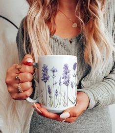 a woman holding a coffee mug with lavender flowers on it