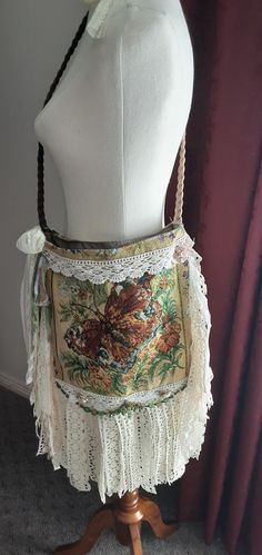 a white mannequin with a floral purse on it's back, sitting on a wooden stand