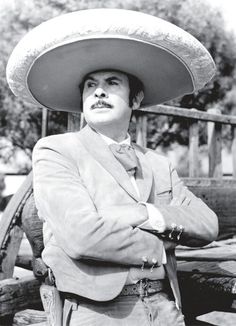 a man wearing a sombrero standing with his arms crossed