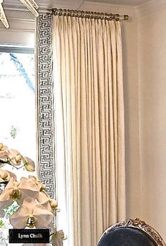 a living room filled with furniture next to a window covered in white curtains and flowers