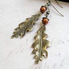 "Here is a lovely pair of oak leaf earrings, comprised of solid brass gold leaf charms, along with copper glass beads, which look like tiny acorns sitting atop the leaves. Earrings come on brass ear wires and are light weight and comfortable to wear. Adorable earrings, perfect for the nature lover! Made in the USA Oak keaf charms measure: 5/8\" x 1.5\" more from my collection here: http://www.etsy.com/shop/botanicalbird About: Botanical Bird is a collection of handcrafted fashion jewelry, both n Leaf Earrings Gold, Oak Leaf Earrings, Oak Leaf Necklace, Earrings Nature, Gold Bar Earrings, Earrings Fall, Gold Leaf Earrings, Fall Earrings, Leaf Jewelry