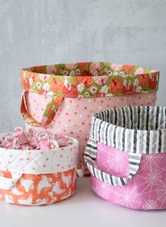 three fabric storage baskets sitting on top of a white table next to each other,