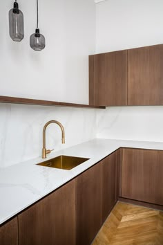 a kitchen with marble counter tops and wooden cabinets, gold faucet in the center