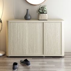 a pair of shoes sitting on top of a wooden cabinet next to a round mirror