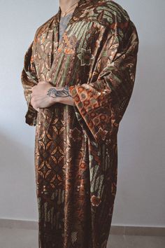 Mens Brown Gold Green Floral Kimono Robe: Sophisticated Design: Handcrafted long floor length kimono adorned with an elegant brown floral pattern complemented by refined gold and green accents for a luxurious touch. Size: Model normally wears size S.  Kimono can fit XS/S/M/L Silk Elegance: Crafted with exquisite silk blend fabric in a sleek brown hue, intricately woven with a stunning floral design for a chic and opulent appearance. Open-Front Style: Provides a relaxed, graceful fit, blending tr Festive Kimono With Kimono Sleeves, Bohemian Long Sleeve Kimono For Eid, Traditional Robe With Kimono Sleeves For Festivals, Traditional Long Sleeve Kurta For Loungewear, Traditional Long Sleeve Robe For Festival, Festival Long Sleeve Kurta With Dabka, Festival Long Sleeve Kurta With Dabka Detailing, Long Sleeve Dabka Kurta For Festival, Festive Vintage Long-sleeve Kurta