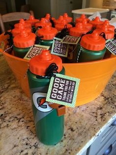 orange and green sports water bottles in a bowl on a kitchen counter with tags attached to them