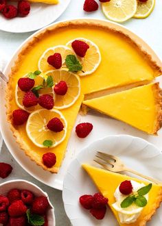 there is a lemon pie with raspberries on the plate and another slice has been cut