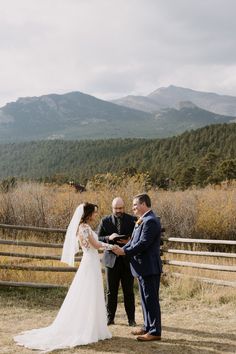 a bride and groom standing at the alter during their wedding ceremony in front of mountains