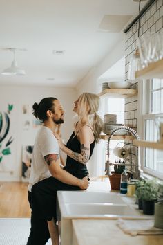 a man and woman standing in front of a kitchen sink with the caption on it