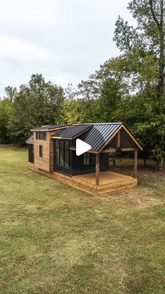 a small wooden cabin sitting on top of a grass covered field with trees in the background