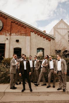 a group of men standing next to each other in front of a building with a clock on it