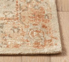 an orange and beige area rug on the floor with wood floors in the background,